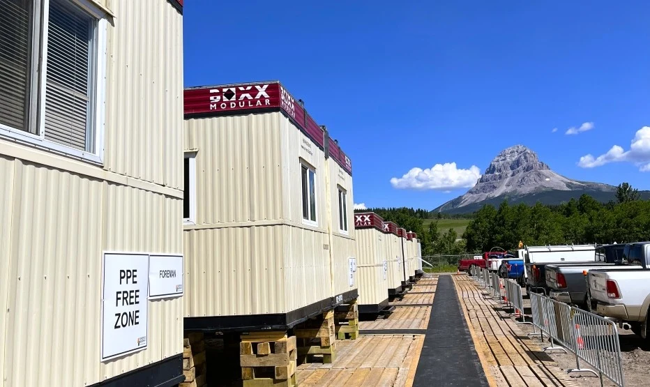 Modular office trailers at a remote construction site with mountains in the background