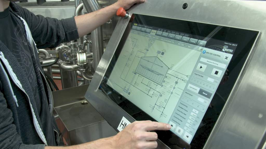 Operator using a plant-floor HMI touch panel to monitor and control industrial equipment